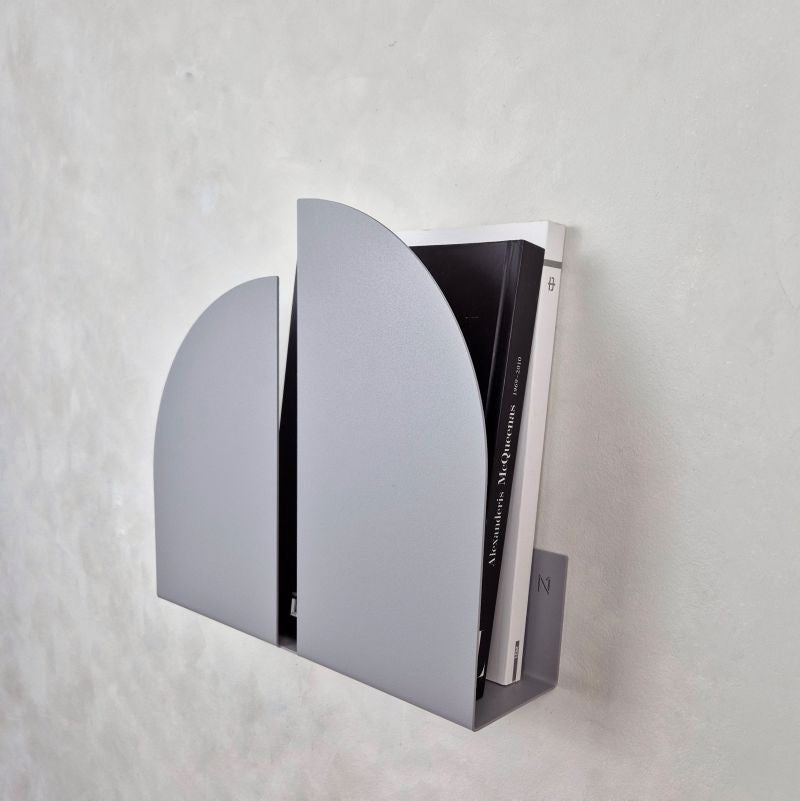 Sieninis žurnalų laikiklis pilkas BAUHAUS su švariomis linijomis ir geometriniu dizainu, laikantis žurnalus ir knygas.