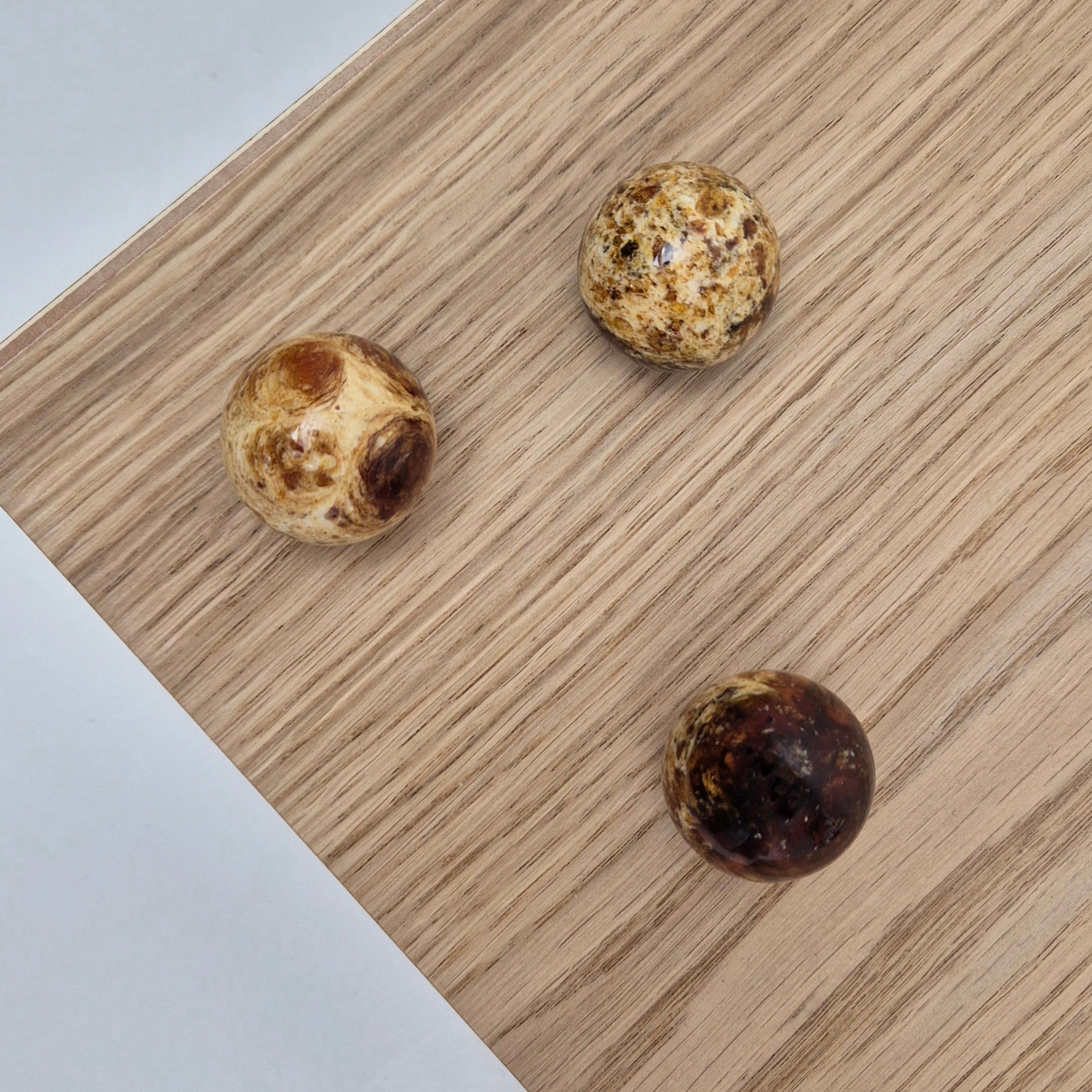 Three round knobs AMBER on a wooden surface, showcasing the intricate design and luxurious material quality.