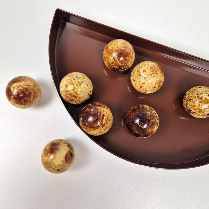 Round knob AMBER displayed on a brown dish, showcasing multiple amber knobs with unique patterns.