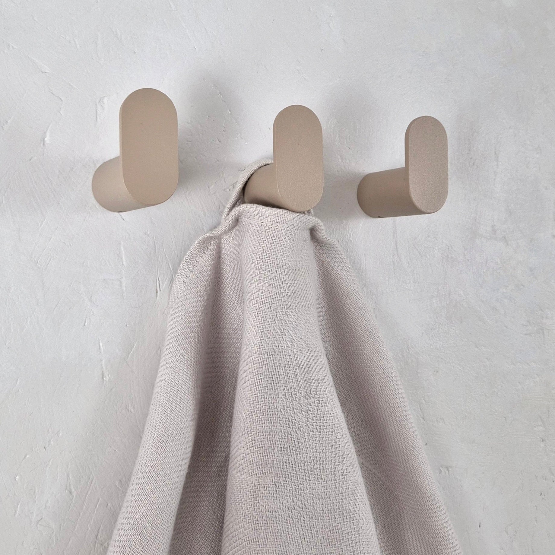 Minimalist wall hook in a modern setting holding a soft blanket, showcasing clean lines and a Scandinavian design.