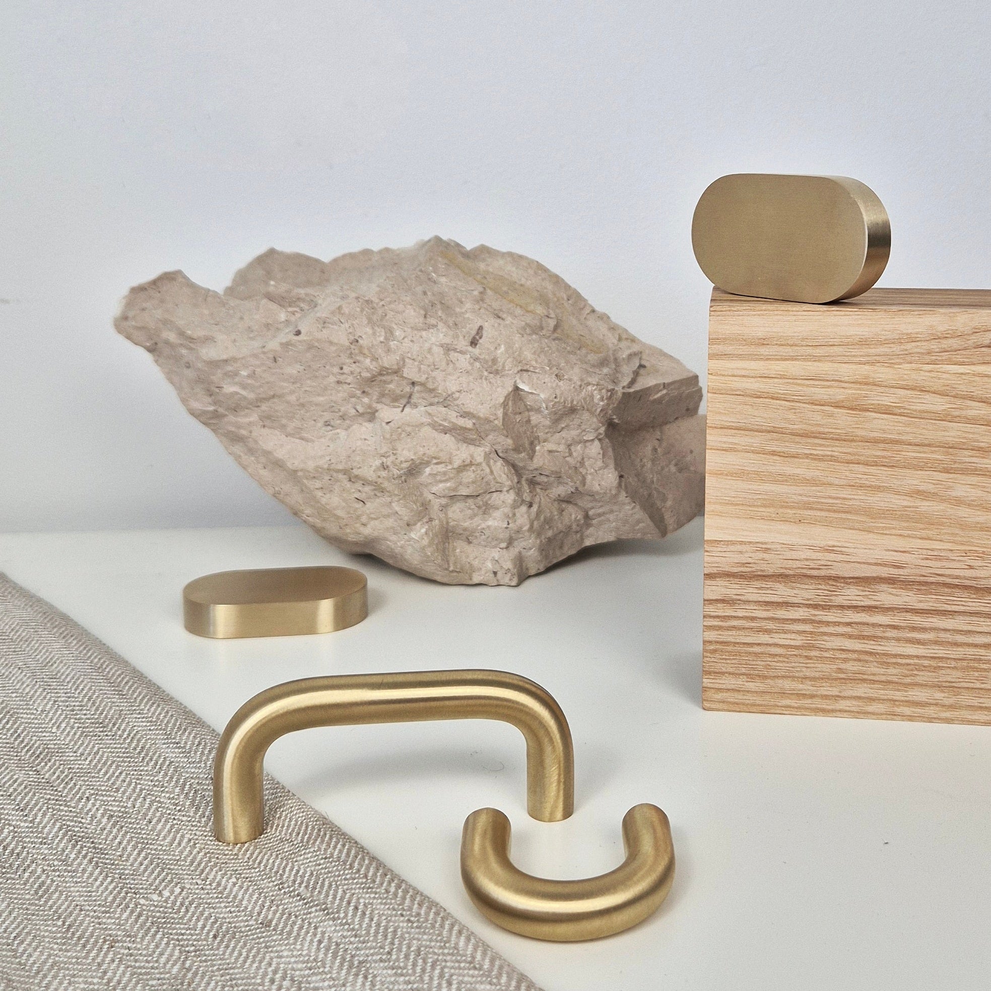 Brass cabinet pull designs displayed with natural stone and wood elements.