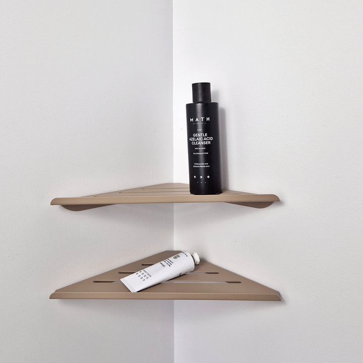 Beige shower corner shelf holding a black cleanser and a white tube, designed for minimalist bathroom storage.