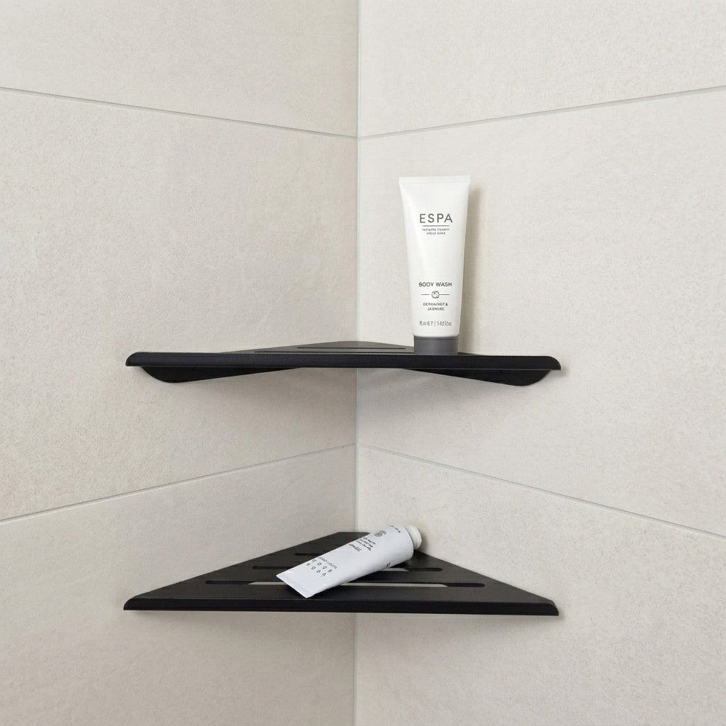 Black shower corner shelf with toiletries on two levels in a minimalist bathroom corner.