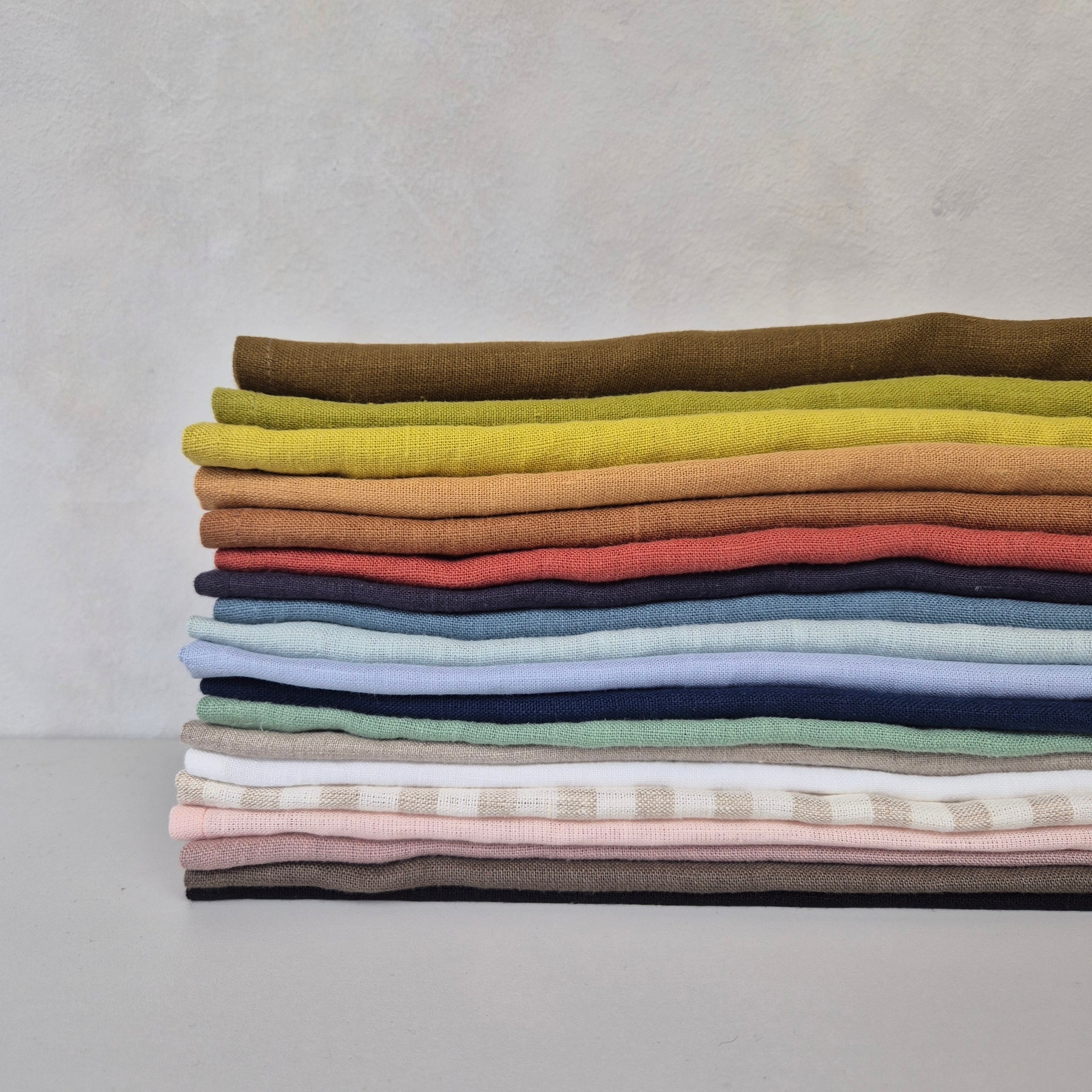Colorful linen napkins in various shades, showcasing the natural texture and softness of 100% linen.