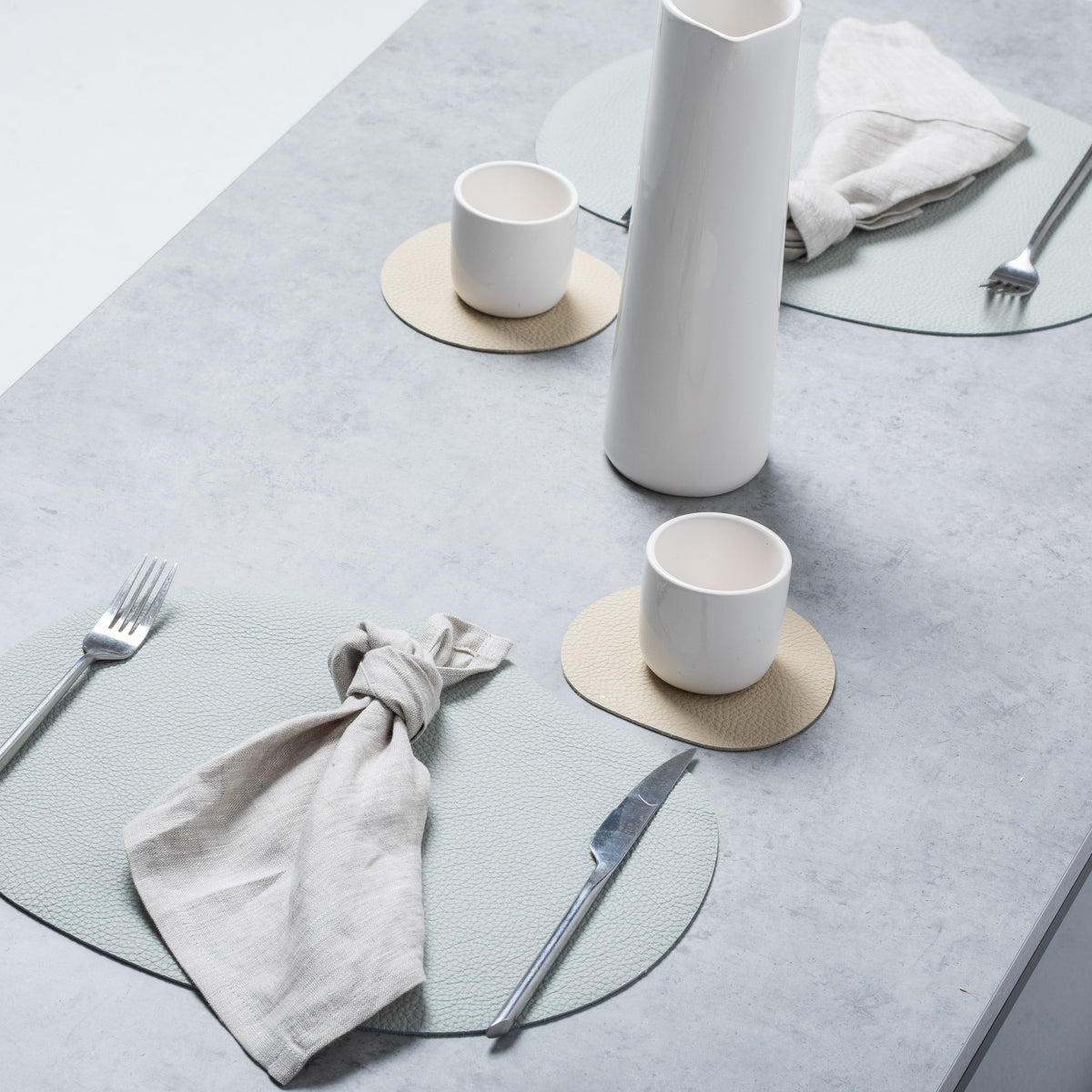 Light grey leather placemat and coaster set on a modern table setting, showcasing elegant design and functionality.