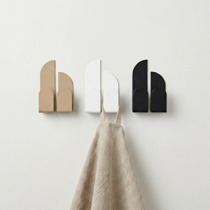 Adhesive wall hooks in beige, white, and black showcasing a minimalist design on a wall.