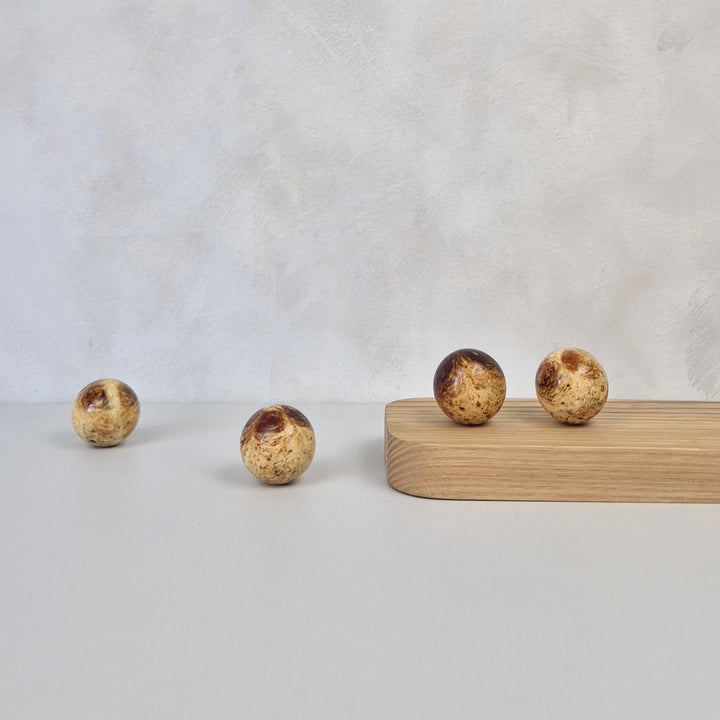 Round amber knob displayed on a wood surface, showcasing modern design and luxurious material.