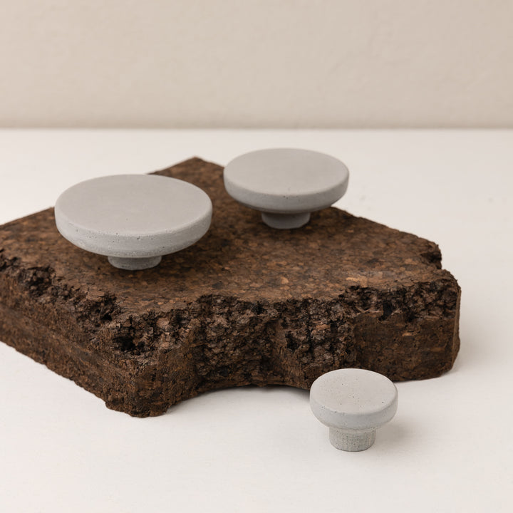 Light grey concrete wall hook set displayed on a natural cork surface, showcasing handmade craftsmanship.