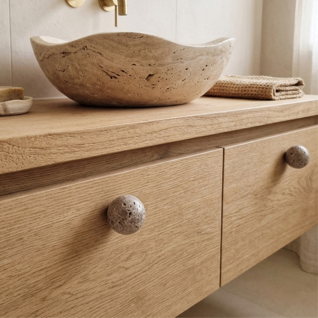 Natural stone cabinet knob on a wooden drawer with a stone bowl and towels, showcasing earthy elegance in home decor.
