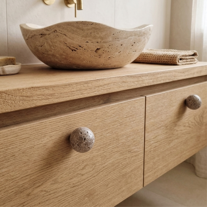 Natural stone cabinet knob on a wooden drawer with a stone bowl and towels, showcasing earthy elegance in home decor.