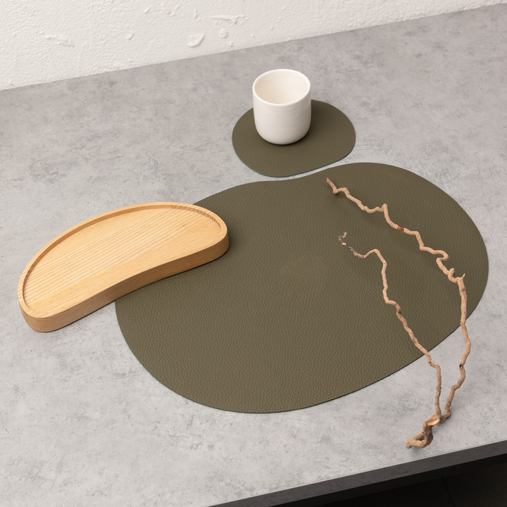 Olive green leather placemat and coaster from MILLSTONES, featuring organic shapes and minimalist design.