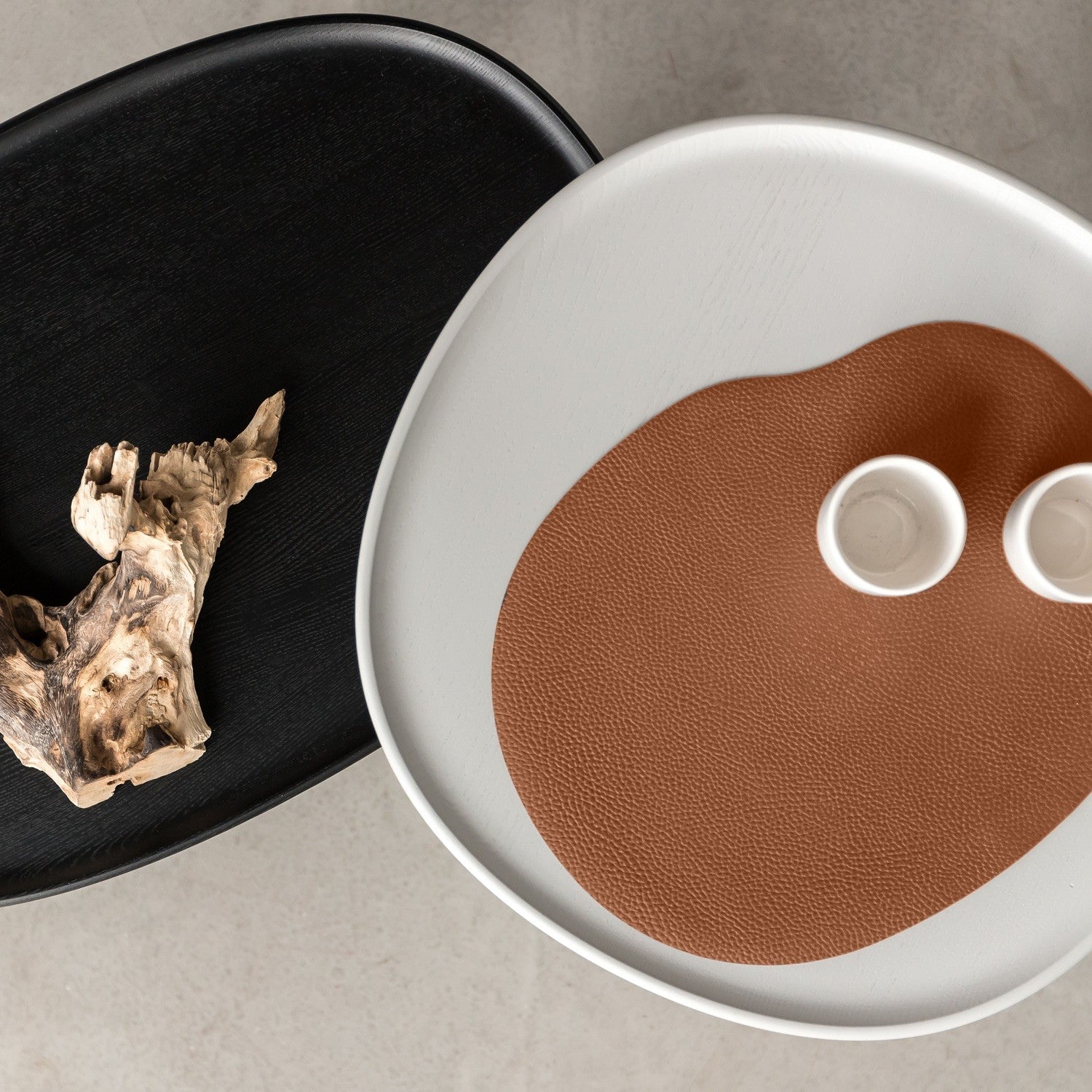 Terracotta Leather placemat featuring an organic wavy shape with white cups on a light-colored table.
